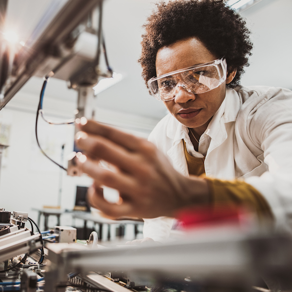 An employee who is a veteran adjusts a high-tech machine in a lab